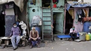 Habitants assis devant leurs logements dans un quartier de bidonvilles urbains