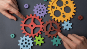 Rouages colorés manipulés à la main illustrant l’innovation et le progrès technique en économie