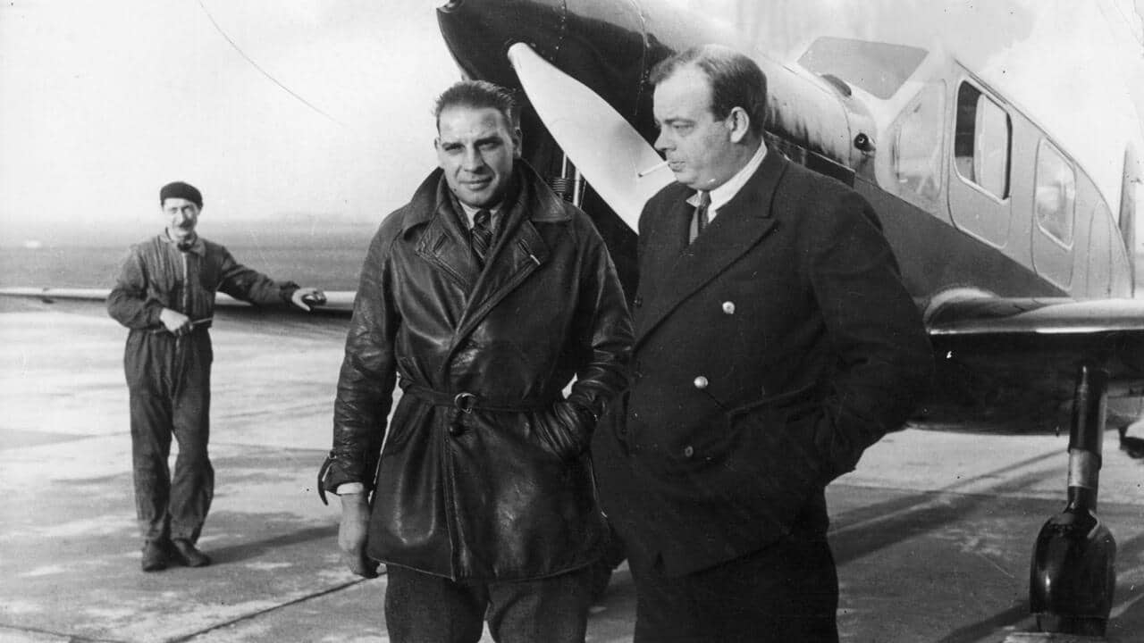 Photographie de Saint-Exupéry en tenue d’aviateur, aux côtés de pilotes, illustrant son engagement humain et aérien.