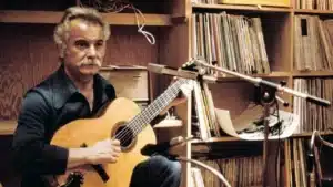 Georges Brassens dans son studio d’enregistrement avec sa guitare, symbole de la chanson française poétique et intemporelle.