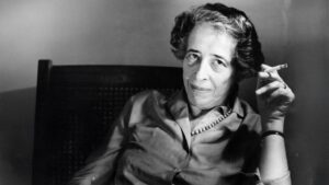 Portrait en noir et blanc de Hannah Arendt tenant une cigarette, philosophe majeure de la pensée politique du XXᵉ siècle.
