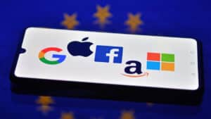 Logos de Google, Apple, Facebook, Amazon et Microsoft sur fond de drapeau européen, symbolisant la bataille numérique entre l’Europe et les FTNs.