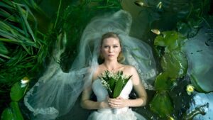Image du film Melancholia de Lars von Trier montrant Kirsten Dunst en robe de mariée allongée dans l’eau, symbole de mélancolie et de fin du monde.