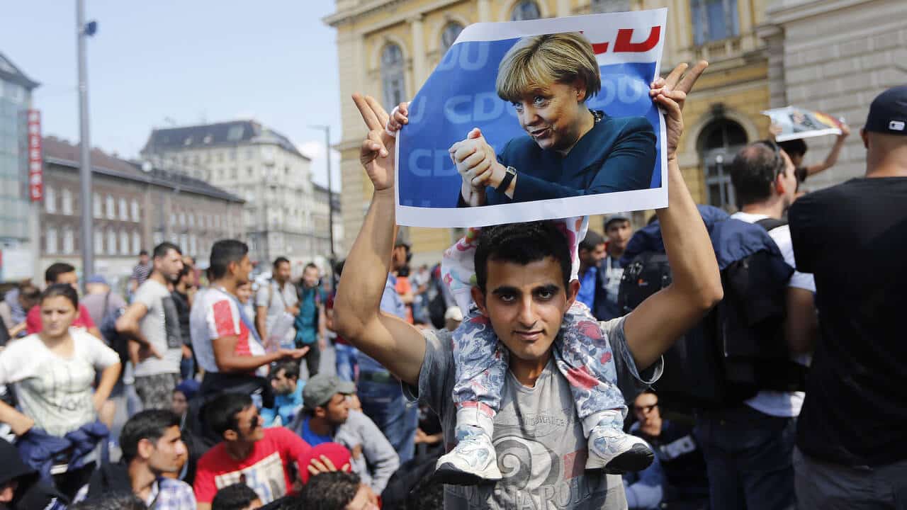 Manifestants tenant une affiche lors des migrations internationales et de la politique migratoire allemande.