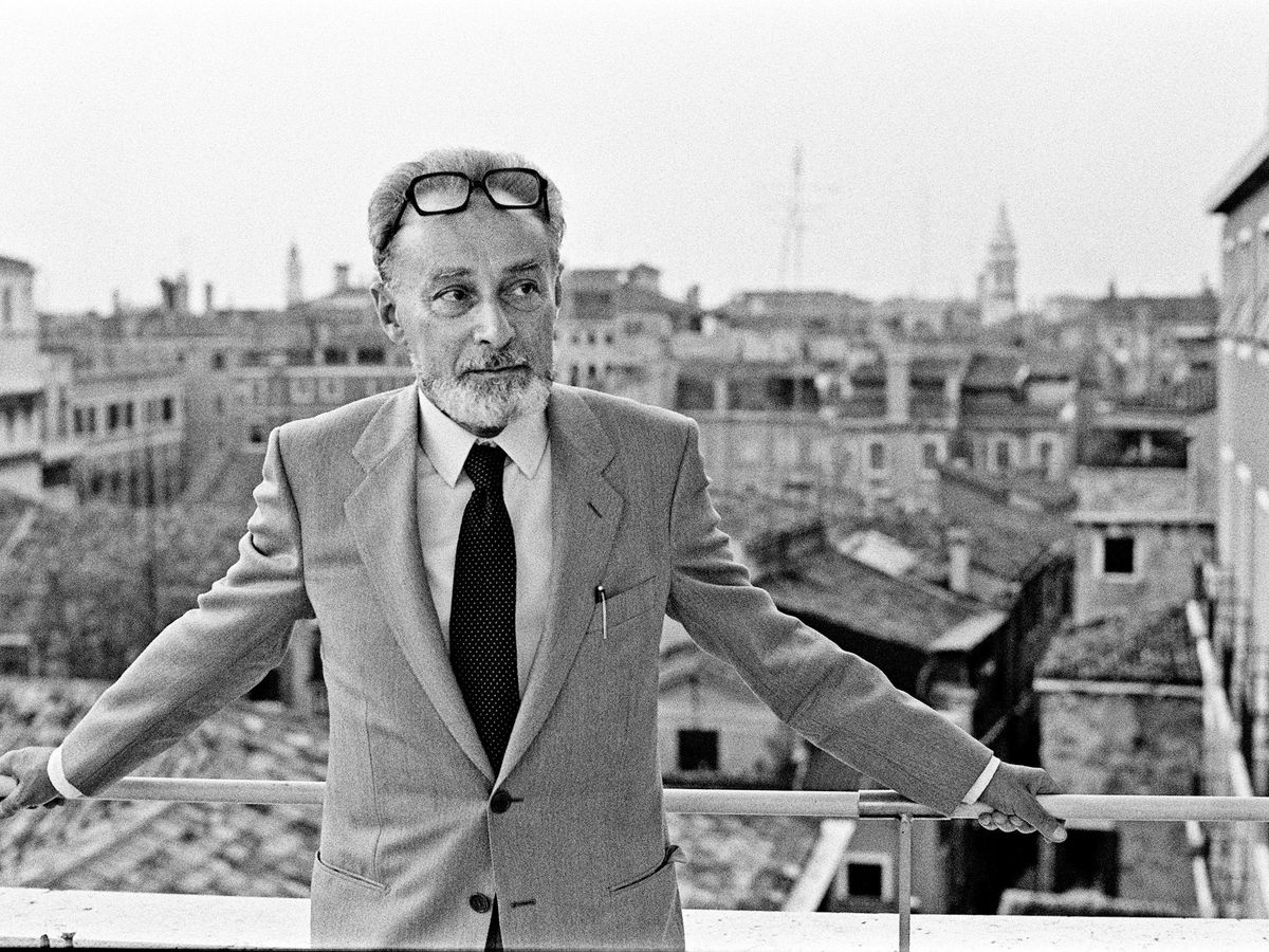 Portrait de Primo Levi en costume, bras ouverts sur un balcon à Turin