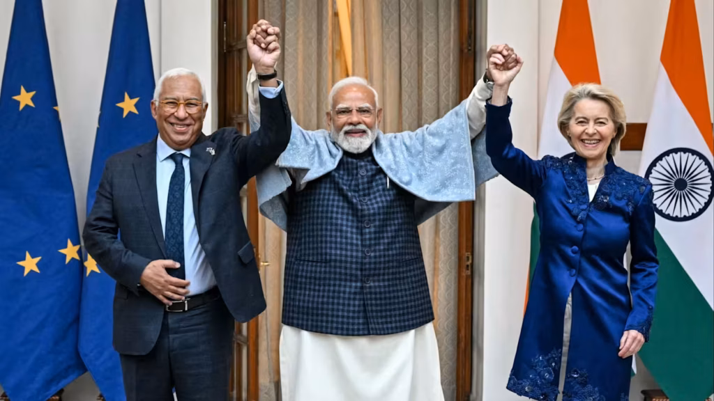 António Costa, Narendra Modi et Ursula von der Leyen se tenant la main levée devant les drapeaux de l'Union européenne et de l'Inde, symobolisant l'alliance avec l'Occident.