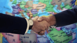 Poignée de main symbolisant un accord commercial international du GATT sur fond de carte du monde