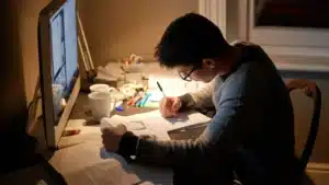Étudiant concentré le soir devant son bureau, prenant des notes pour mémoriser les expressions idiomatiques en anglais