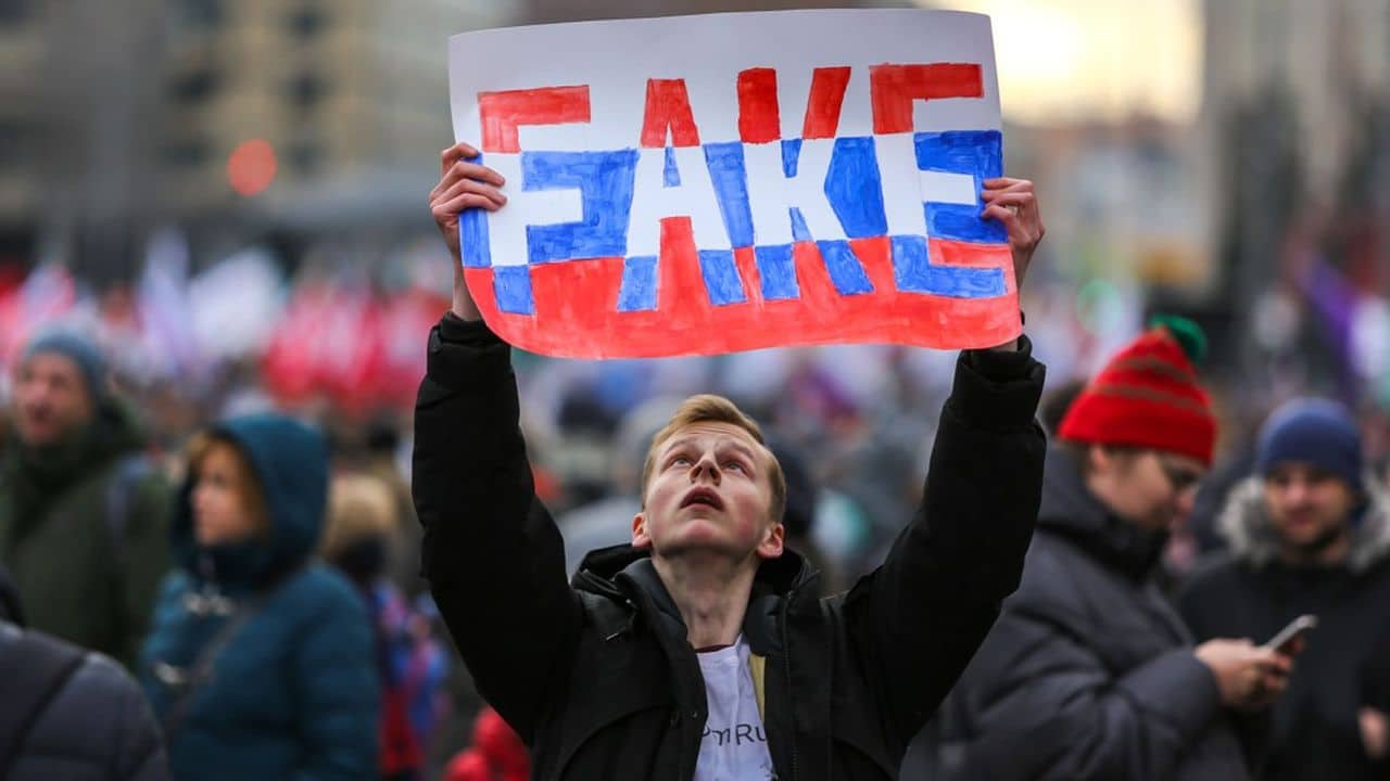 Manifestant dénonçant la désinformation, symbole de la guerre hybride russe.