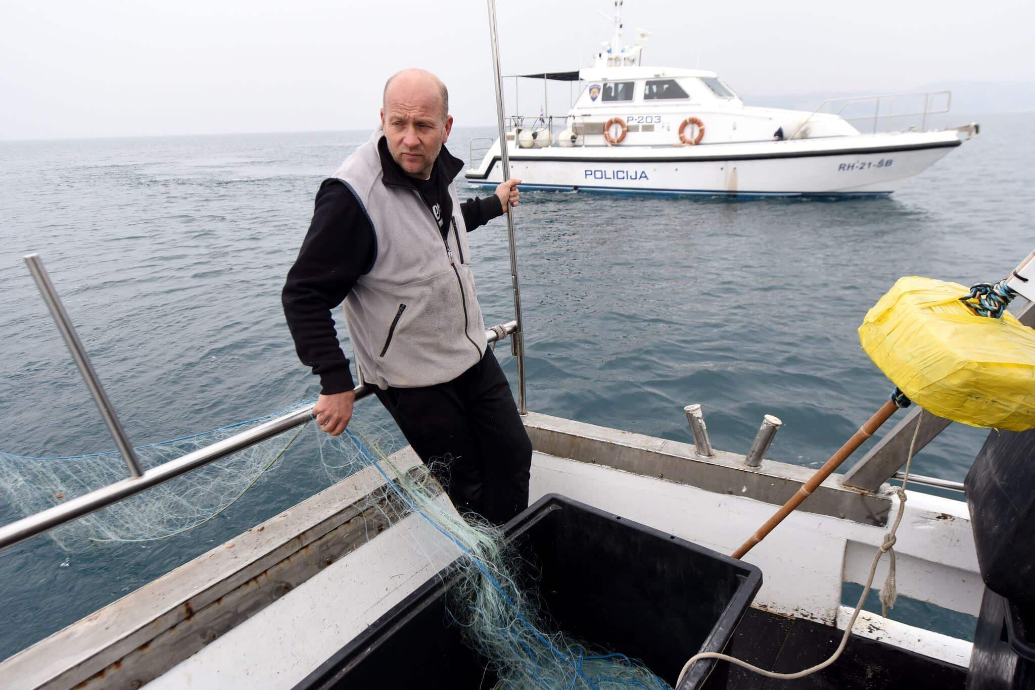 Un pêcheur slovène jette ses filets dans la baie de Piran, zone contestée entre la Slovénie et la Croatie, symbole des tensions frontalières en mer Adriatique.