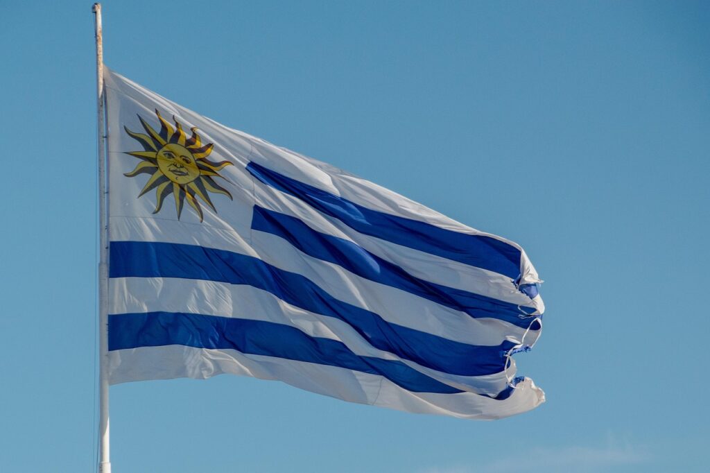 Drapeau de l’Uruguay flottant au vent, symbole d’un pays laïque, démocratique et socialement avancé, incarnant les valeurs de sobriété et de cohérence politique portées par José “Pepe” Mujica.