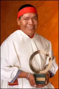 Isidro Baldenegro souriant en tenue traditionnelle tenant un prix environnemental dans ses mains.
