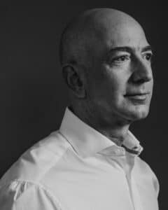 Portrait en noir et blanc de Jeff Bezos en chemise blanche, regard tourné vers la droite.