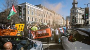 Des manifestants chrétiens et des militants de Youth Demand bloquent une rue de Londres avec des pancartes dénonçant les ventes d’armes britanniques à Israël.