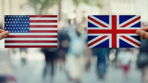 Deux mains tiennent les drapeaux des États-Unis et du Royaume-Uni face à face, illustrant les différences entre l’anglais américain et l’anglais britannique.