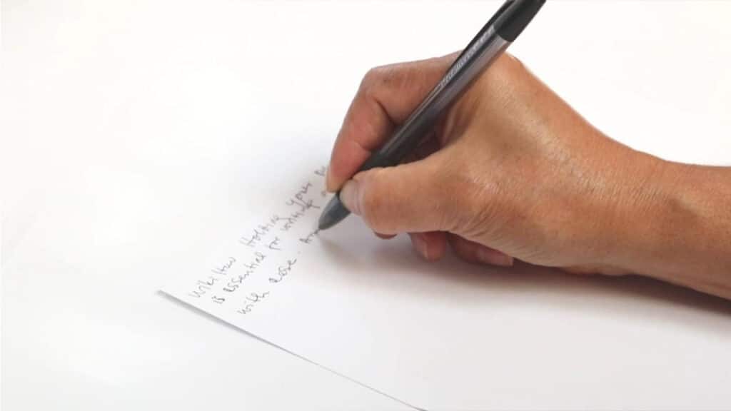 Main rédigeant à la main la conclusion d'une dissertation de philo sur feuille blanche