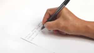 Main rédigeant à la main la conclusion d'une dissertation de philo sur feuille blanche