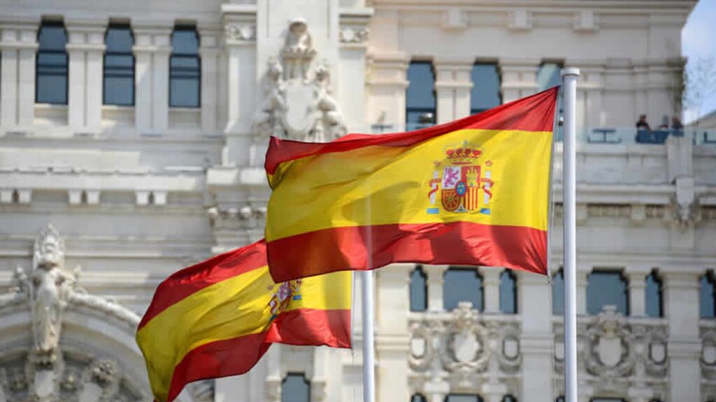 Deux drapeaux espagnols flottant devant un palais de Madrid, illustration de la concordance des temps en espagnol