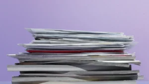 Pile de documents et magazines sur fond violet, illustration de la méthode de contraction de texte