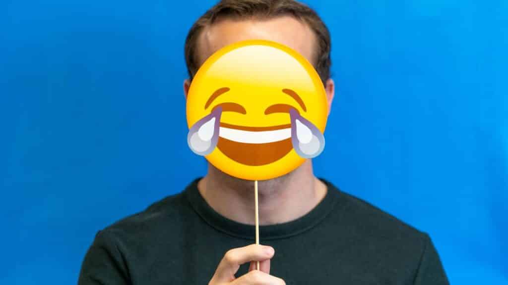 Homme tenant un emoji riant illustrant les devinettes en anglais