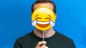 Homme tenant un emoji riant illustrant les devinettes en anglais