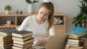 Étudiante entourée de livres travaillant sur son essay, illustration des expressions pour l'essay en anglais