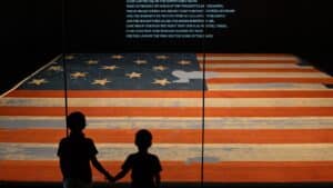 Deux enfants regardent la bannière étoilée originale, symbole des grandes dates de l'histoire américaine