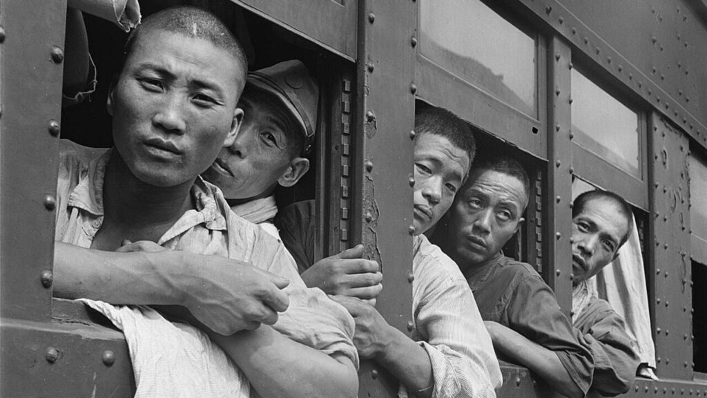 Hommes japonais regardant par les fenêtres d'un train, photographie d'époque illustrant l'occupation américaine au Japon