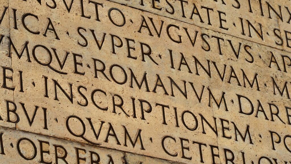 Inscription latine gravée sur pierre, illustrant la pratique du petit latin et du petit grec