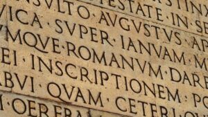 Inscription latine gravée sur pierre, illustrant la pratique du petit latin et du petit grec