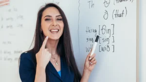 Professeure d'anglais montrant la phonétique au tableau, illustrant l'entraînement au shadowing pour la prononciation anglaise