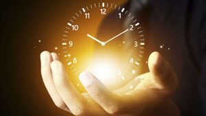 Horloge lumineuse tenue dans des mains, symbole du temps pour réviser since for ago en anglais