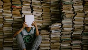 Étudiant entouré de piles de livres révisant les sujets oral anglais