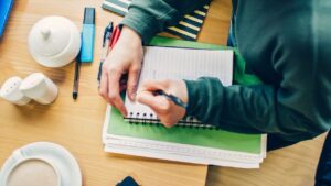 Étudiant prenant des notes dans un carnet, illustration de la pratique des techniques de l'étoffement