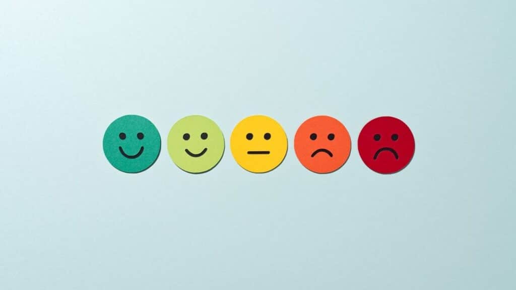 Cinq visages en papier de couleurs différentes exprimant des émotions allant de la joie à la tristesse, illustrant le vocabulaire des émotions en espagnol