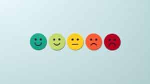 Cinq visages en papier de couleurs différentes exprimant des émotions allant de la joie à la tristesse, illustrant le vocabulaire des émotions en espagnol